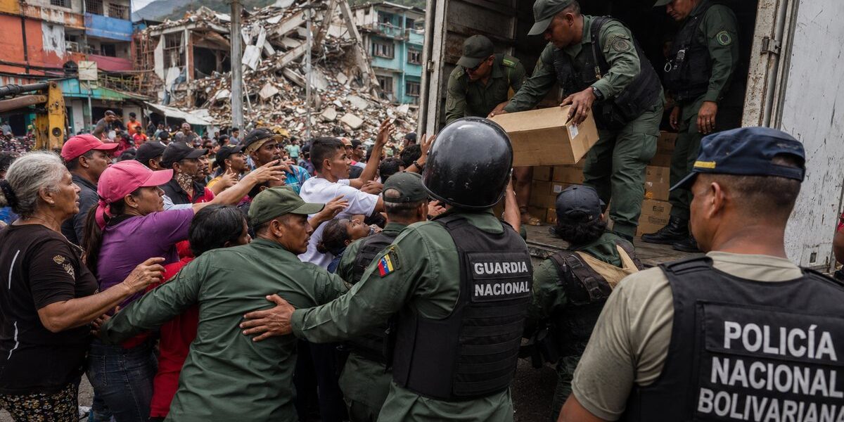 Imagen editorial de fuerzas de seguridad controlando suministros humanitarios frente a una multitud de civiles en una zona urbana afectada por un terremoto, utilizada para ilustrar denuncias sobre desvío de ayuda y obstáculos al rescate en Venezuela.