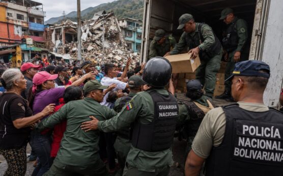 Imagen editorial de fuerzas de seguridad controlando suministros humanitarios frente a una multitud de civiles en una zona urbana afectada por un terremoto, utilizada para ilustrar denuncias sobre desvío de ayuda y obstáculos al rescate en Venezuela.